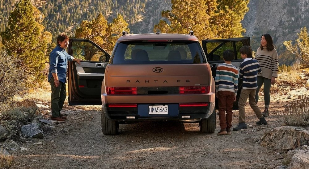 A family is shown near a bronze 2025 Hyundai Santa Fe Hybrid.