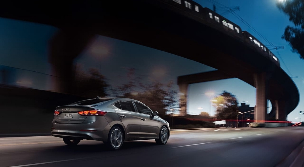 A grey 2017 Hyundai Elantra is driving at night.
