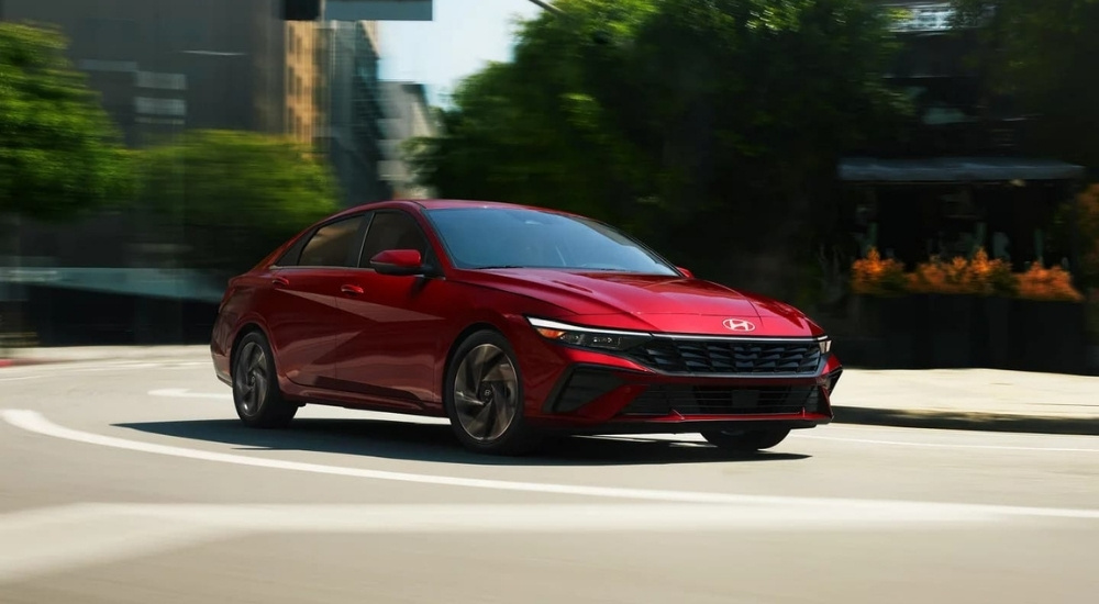 A red 2024 Hyundai Elantra Limited is driving to look at used cars for sale.