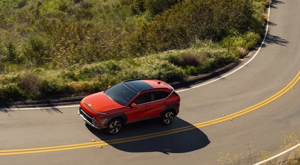A red 2025 Hyundai KONA driving on a highway.