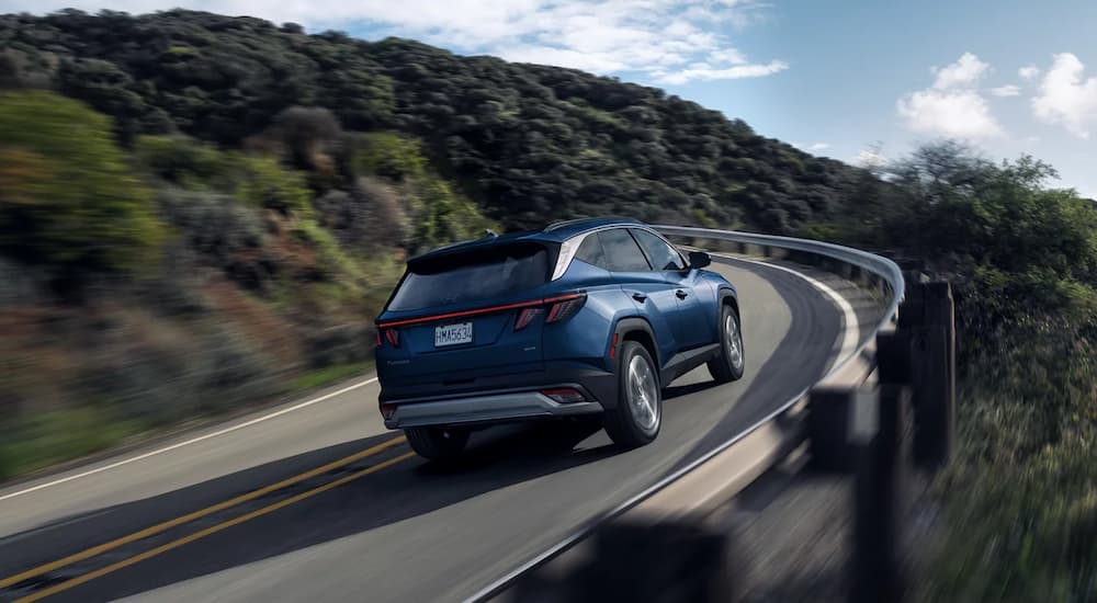 A blue 2026 Hyundai Tucson for sale driving down a highway