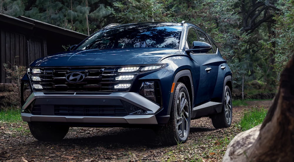 Blue 2026 Hyundai Tucson for sale parked off-road in a forest.