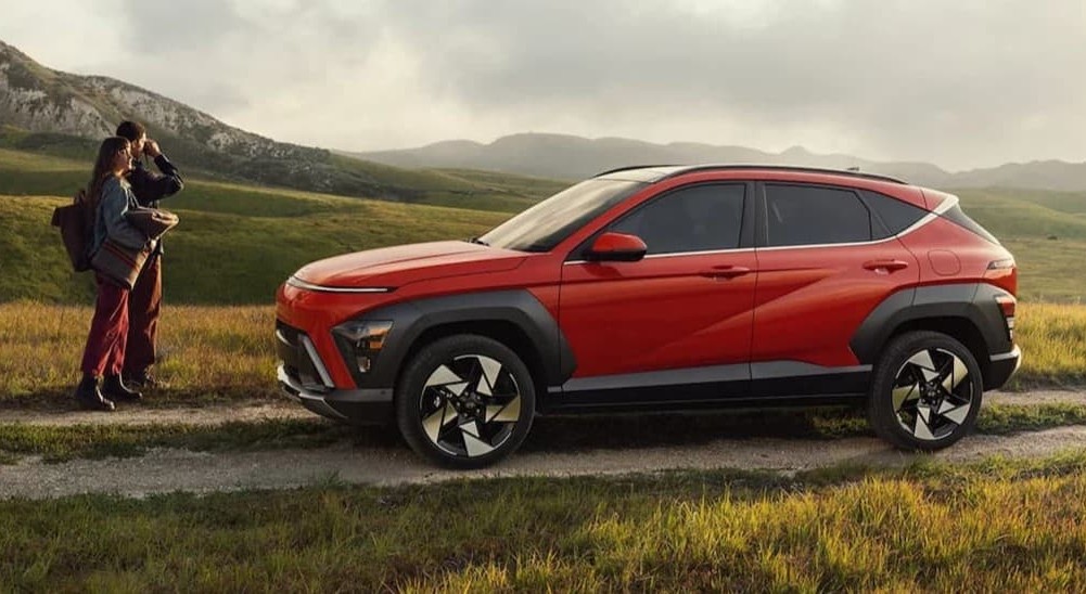 Two people near a red 2026 Hyundai Kona.