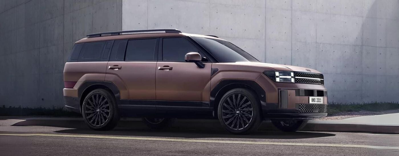 A brown 2024 Hyundai Santa Fe parked by a concrete building.
