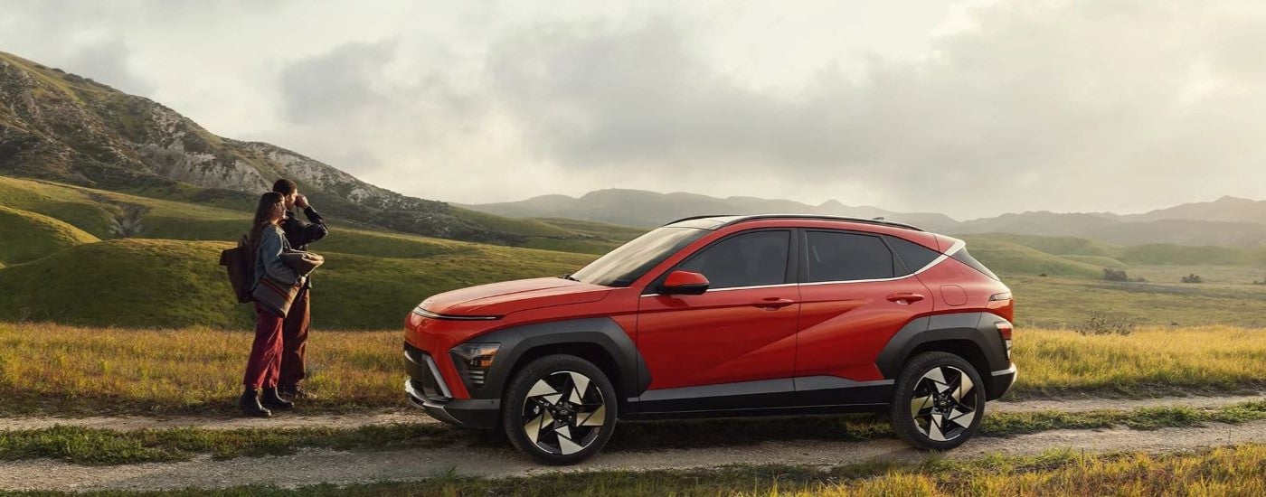A red 2024 Hyundai Kona parked off-road on a trail and angled left.