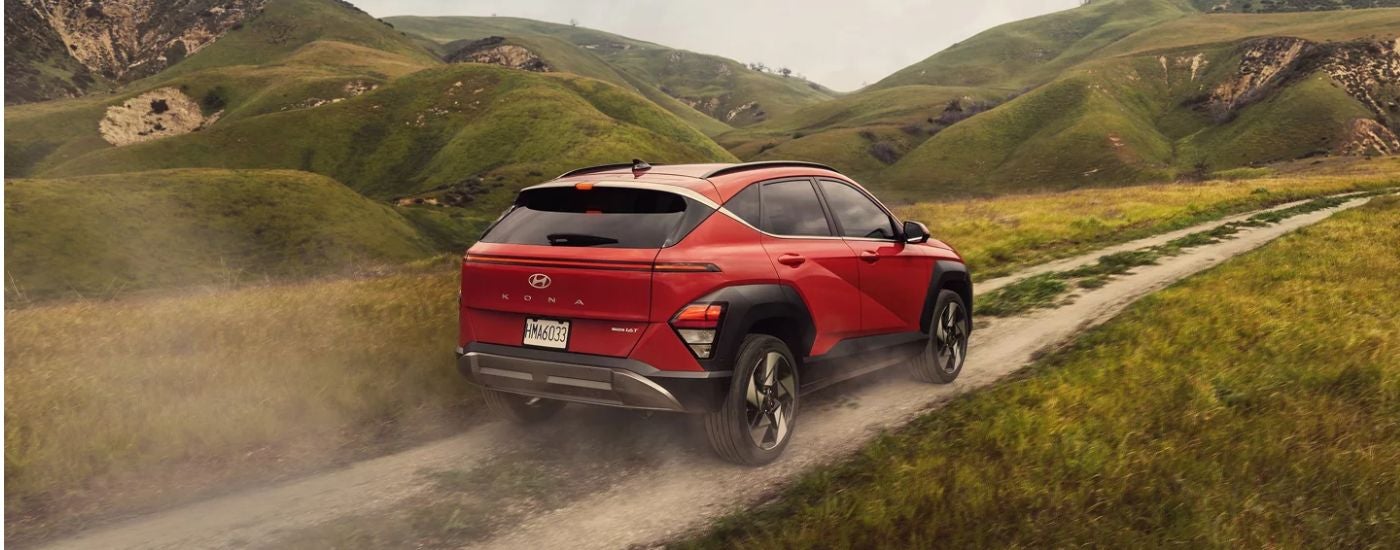 An orange pearl 2026 Hyundai Kona Limited driving a mountainous trail.