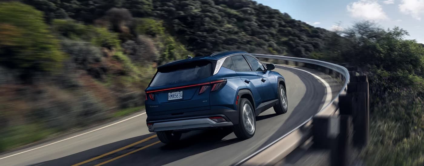 A blue 2025 Hyundai Tucson Limited is driving on a winding highway road.