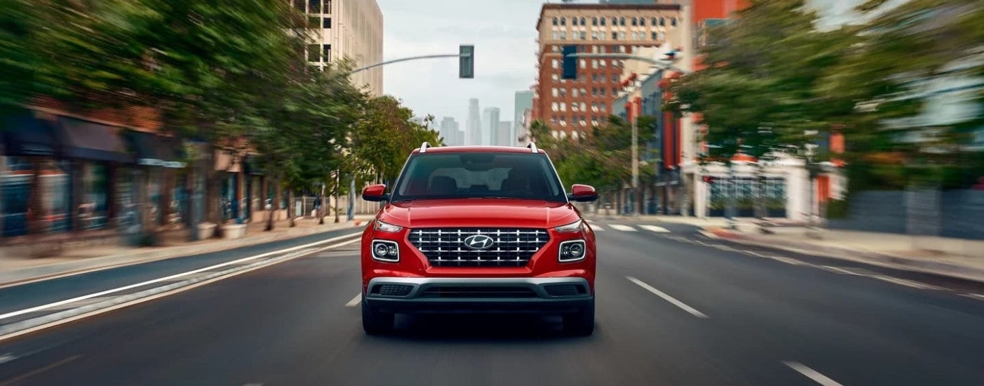 A red 2023 Hyundai Venue Limited is shown from the front driving to a Hyundai dealer.