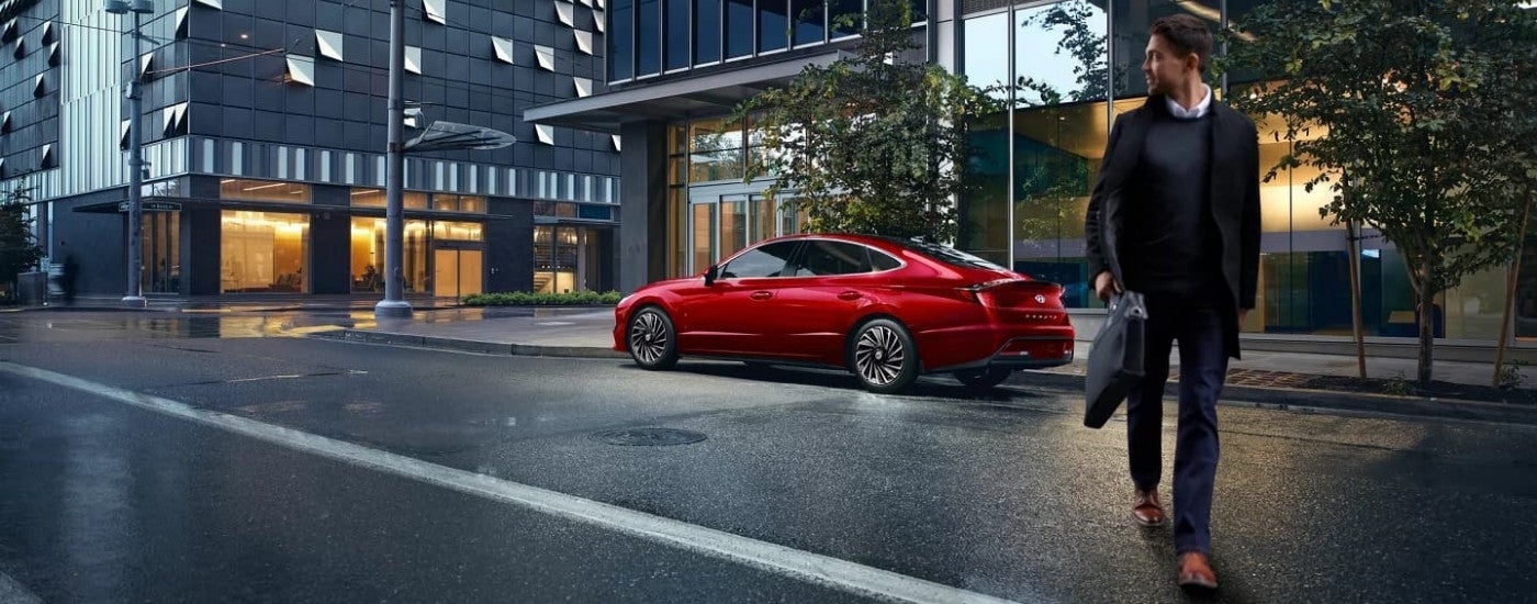 A red 2023 Hyundai Sonata HEV parked on a city street.