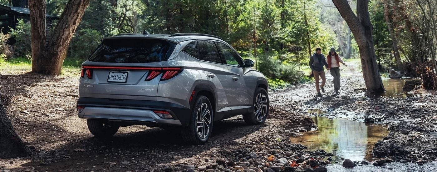 Silver 2025 Hyundai Tucson PHEV Limited parked offroad near hikers