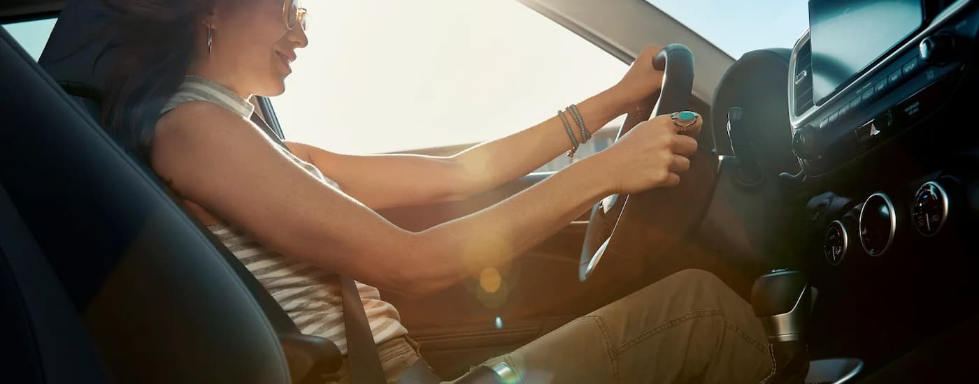 A woman is test driving a 2025 Hyundai Venue for sale at a dealership.